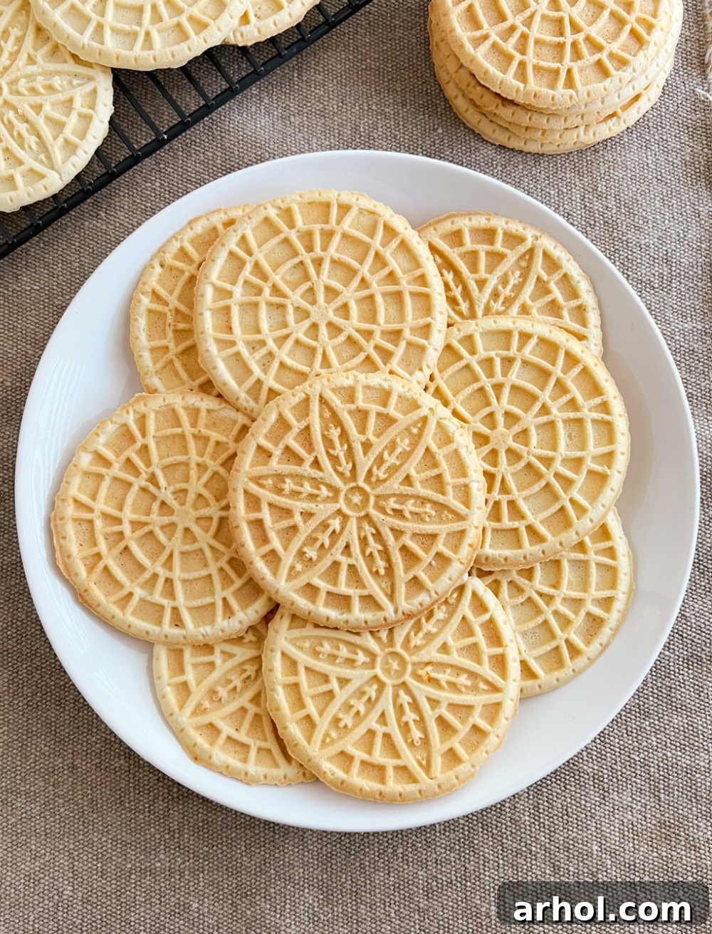 Perfectly stacked and arranged pizzelle cookies on a white plate, ready for serving.