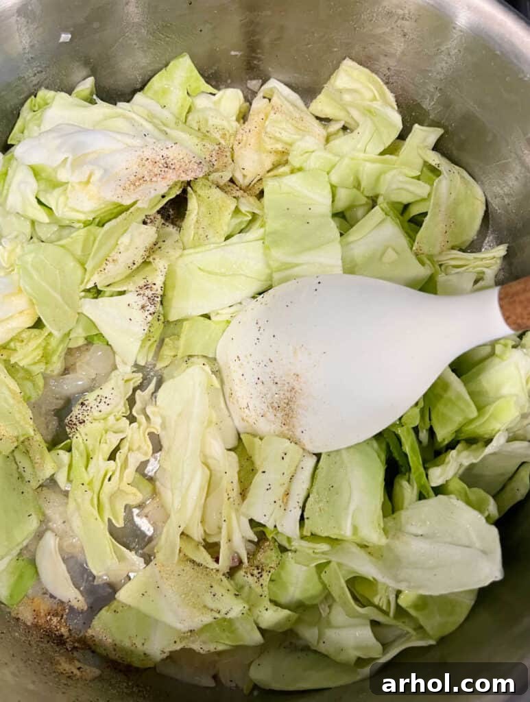 Onions and cabbage cooking in a large pot on the stovetop.