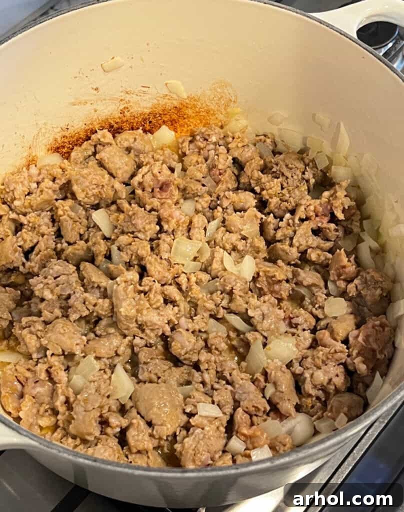 Sautéing crumbled Italian sausage and diced onion in a Dutch oven until browned and soft.