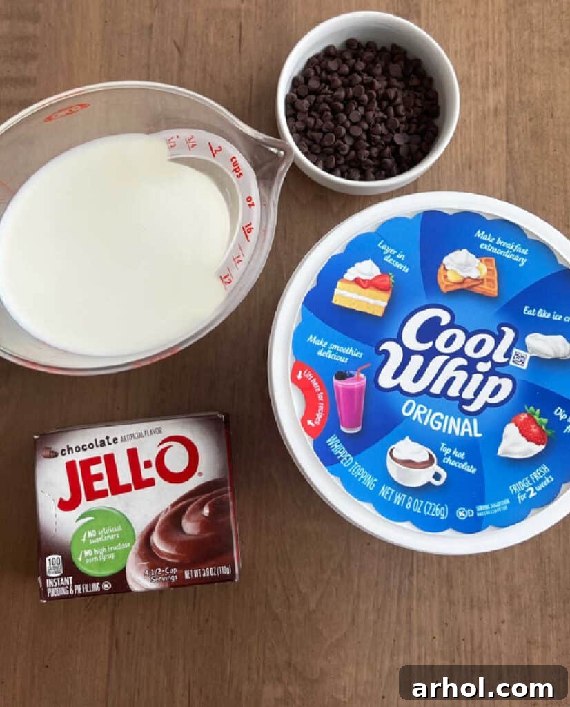 The four simple ingredients: Jell-O instant pudding mix, cold milk, Cool Whip, and mini chocolate chips, laid out on a surface.
