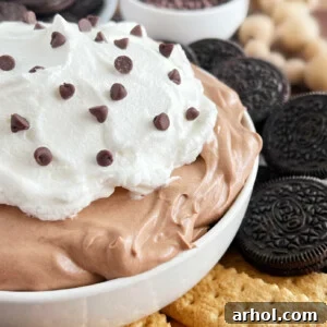 A square image of chocolate pudding pie dip in a bowl with various dippers surrounding it.