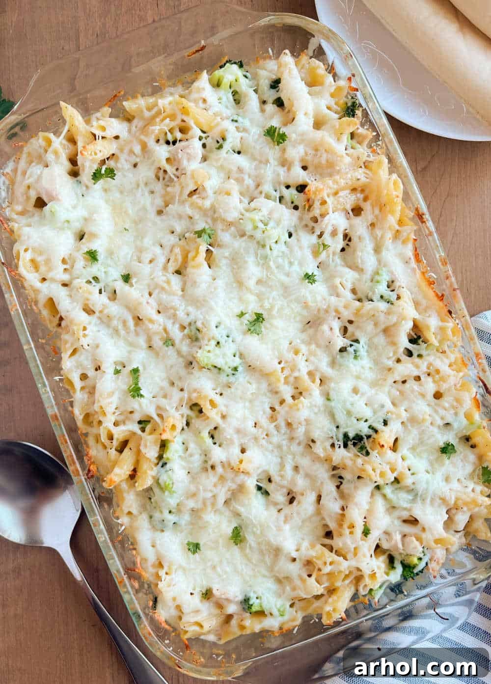 A freshly baked Chicken Broccoli Alfredo Casserole, bubbly and golden with melted mozzarella and Parmesan cheese, ready to be served from a festive table setting.