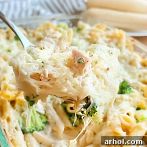 Cheesy Chicken and Broccoli Alfredo Casserole with pasta on a serving spoon, ready to be enjoyed.