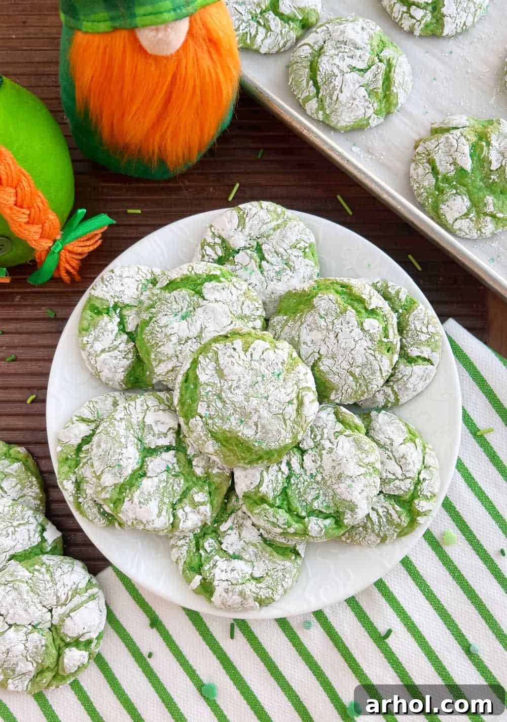 A festive arrangement: St. Patrick's Day cake mix cookies displayed on a white plate, flanked by charming leprechaun gnomes, ready for a holiday celebration.