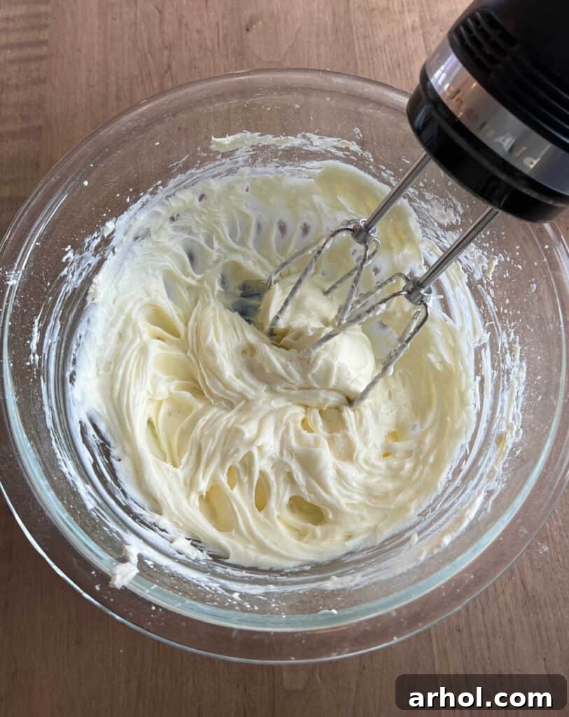 The mixing bowl showing cream cheese and powdered sugar being blended until smooth and creamy.