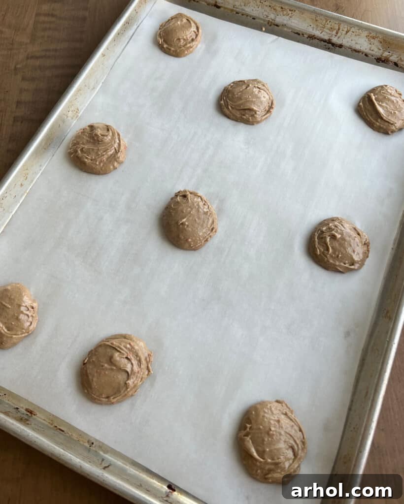 Neatly scooped carrot cookie dough balls arranged on a baking sheet lined with parchment paper, spaced for even baking.