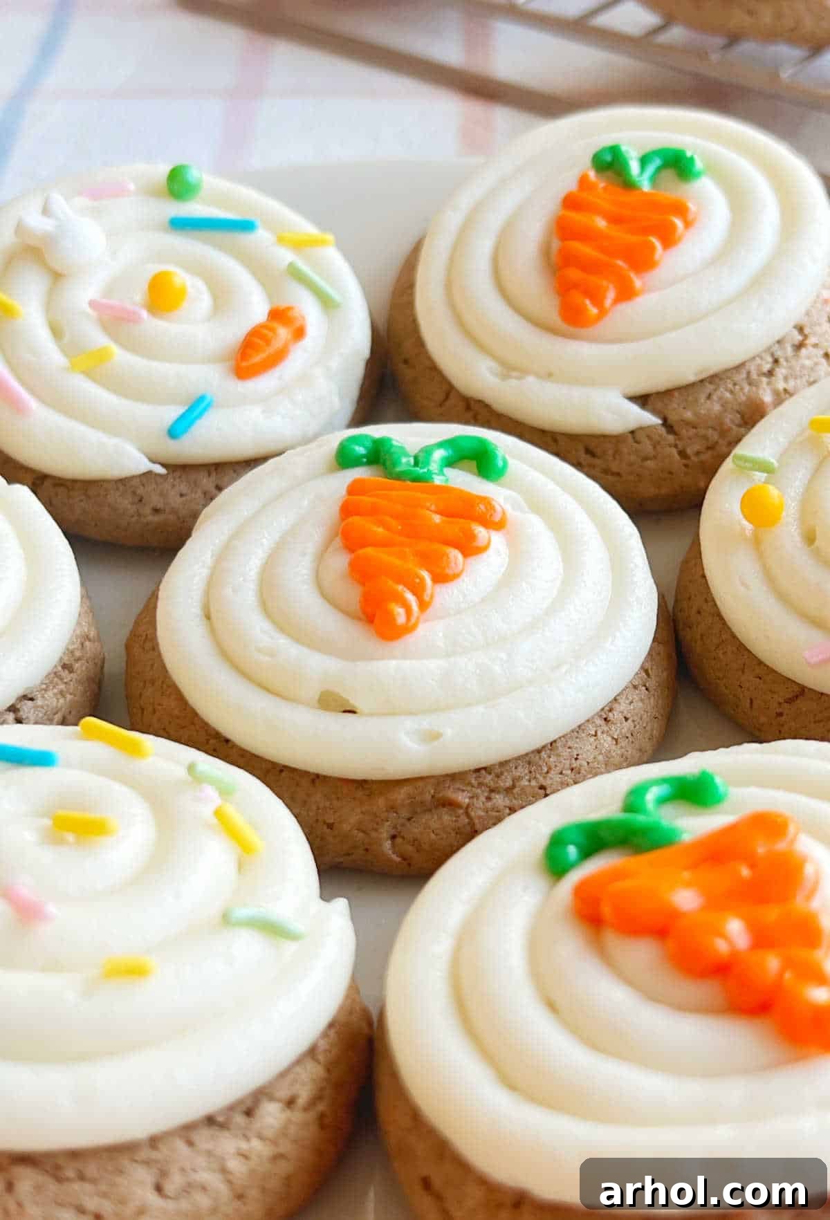 A festive plate of decorated carrot cake cookies, some topped with cream cheese frosting and piped carrots, others with sprinkles, ready to be served.