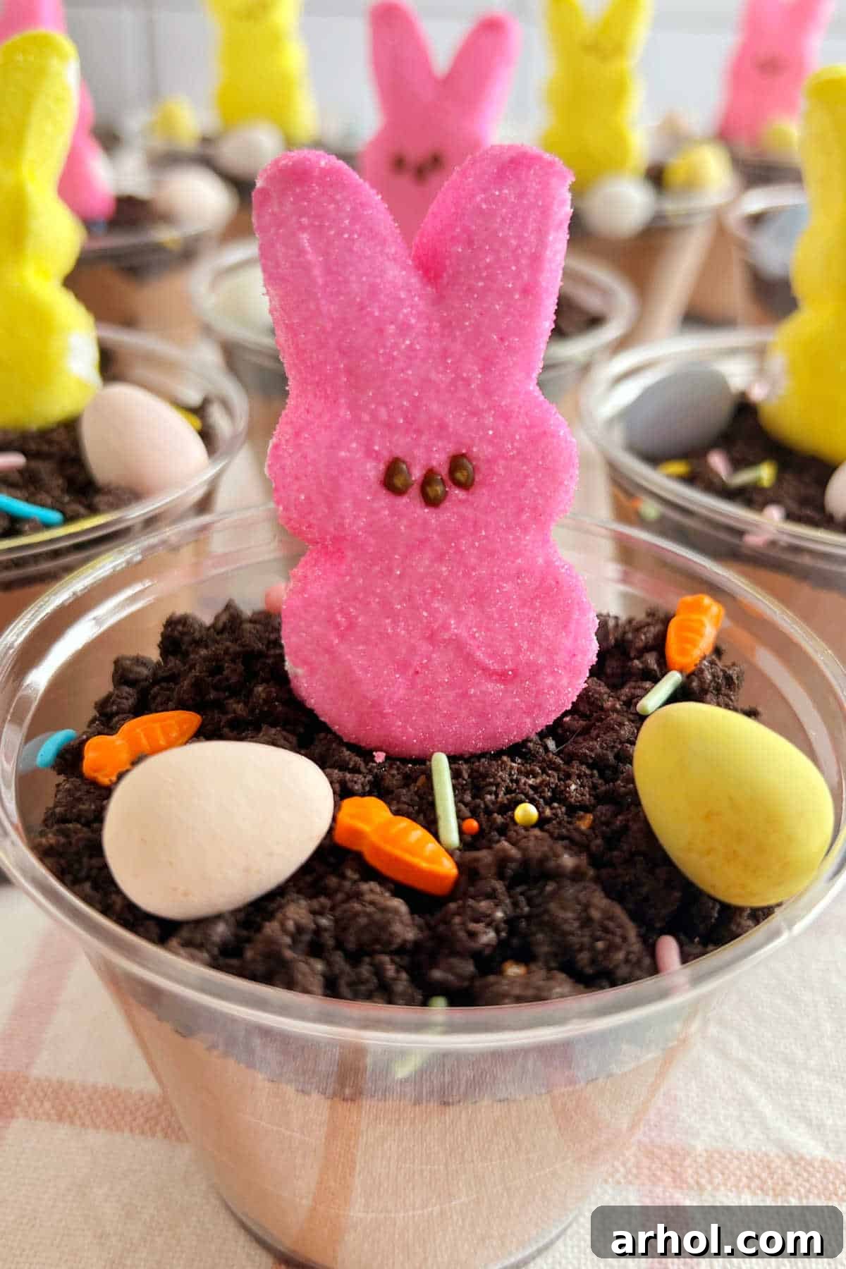 Easter pudding cups with pink peeps bunny and candy eggs in Oreo dirt. A vibrant, no-bake dessert for springtime celebrations.