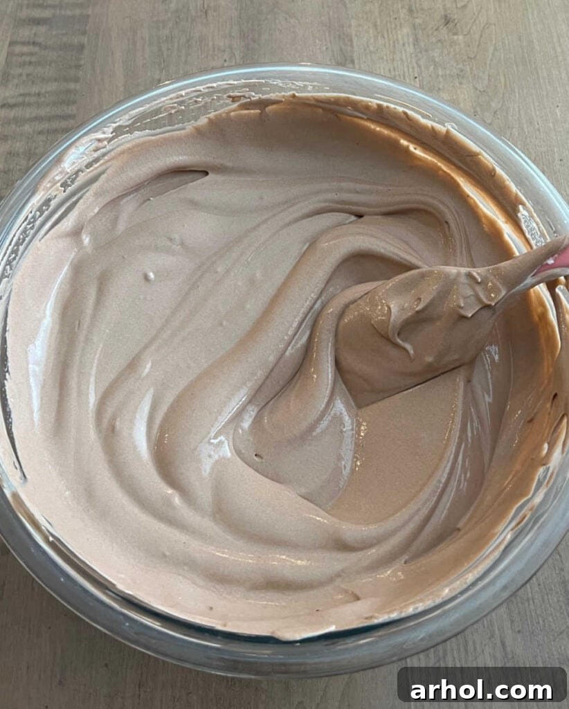 Gently folding thawed Cool Whip into the chocolate pudding mixture with a rubber spatula.