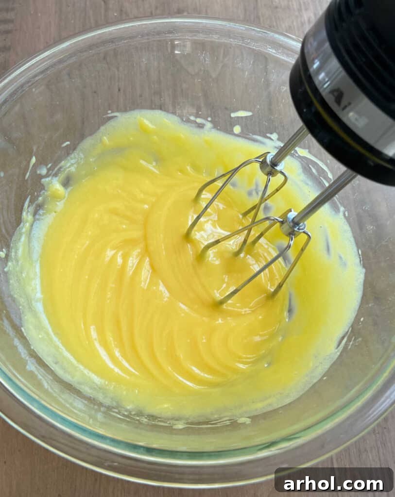 The process of mixing instant vanilla pudding mix with milk in a large bowl, demonstrating the initial step for the pie's creamy filling.