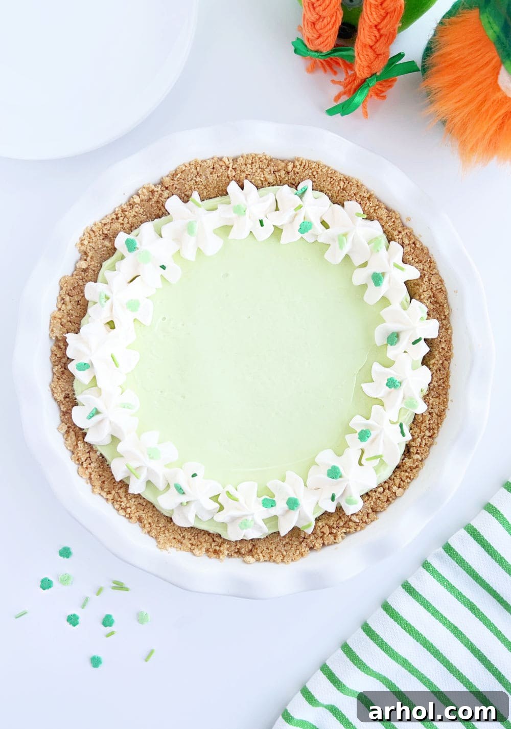 A beautifully prepared St. Patrick's Day pie, vibrant green and adorned with shamrock sprinkles, sitting in a pie dish, ready for chilling and serving.