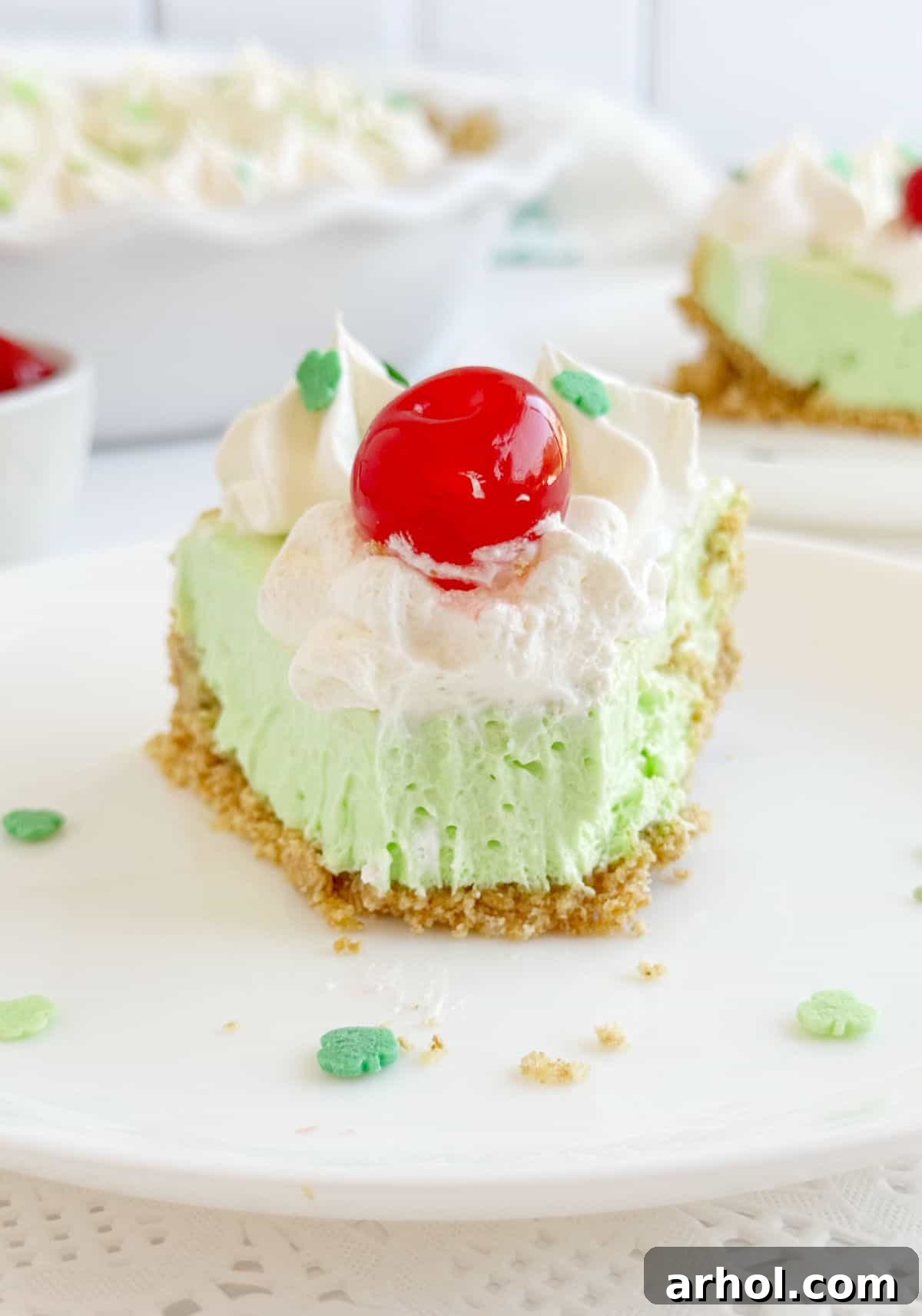 A beautifully presented slice of shamrock pie, topped with a maraschino cherry, served on a white plate. This image is perfect for Pinterest, showing a delicious St. Patrick's Day dessert.