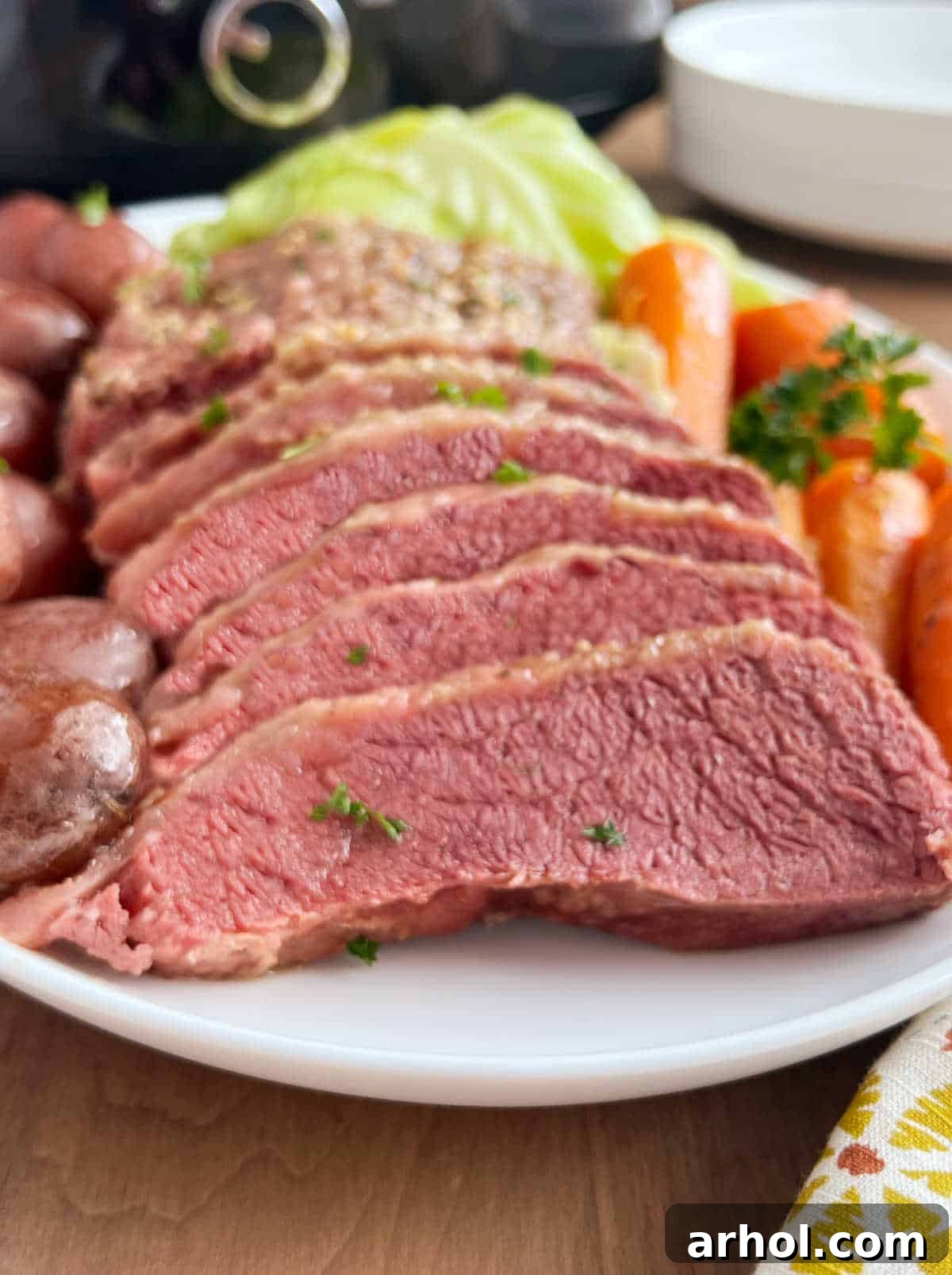 Platter with beautifully sliced corned beef, vibrant cabbage, carrots, and potatoes, ready to serve from the crockpot.