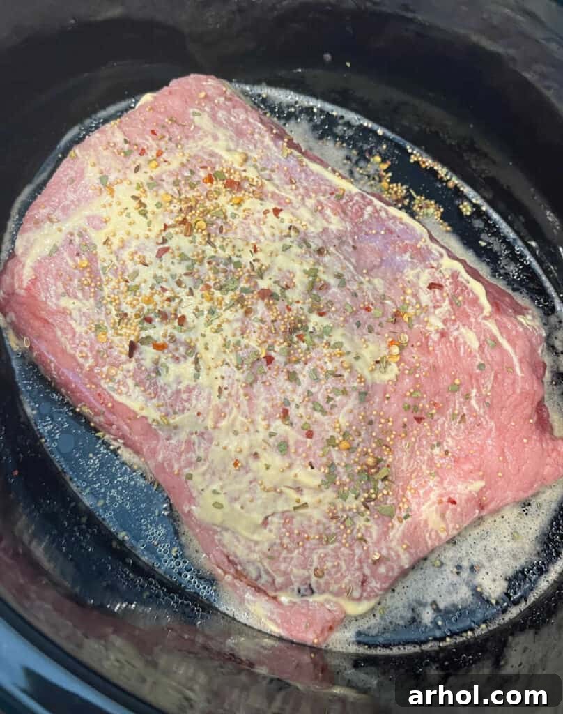 Corned beef brisket seasoned with mustard and Guinness stout in a slow cooker.