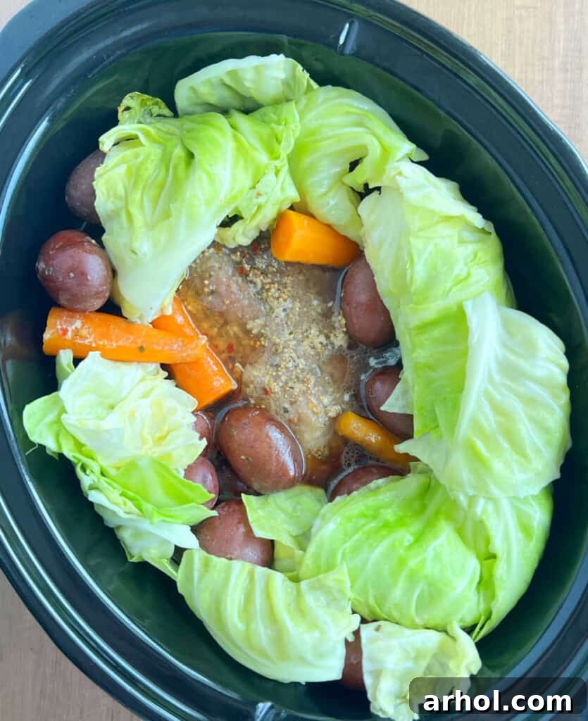 Green cabbage wedges added to the slow cooker with corned beef, carrots, and red potatoes.