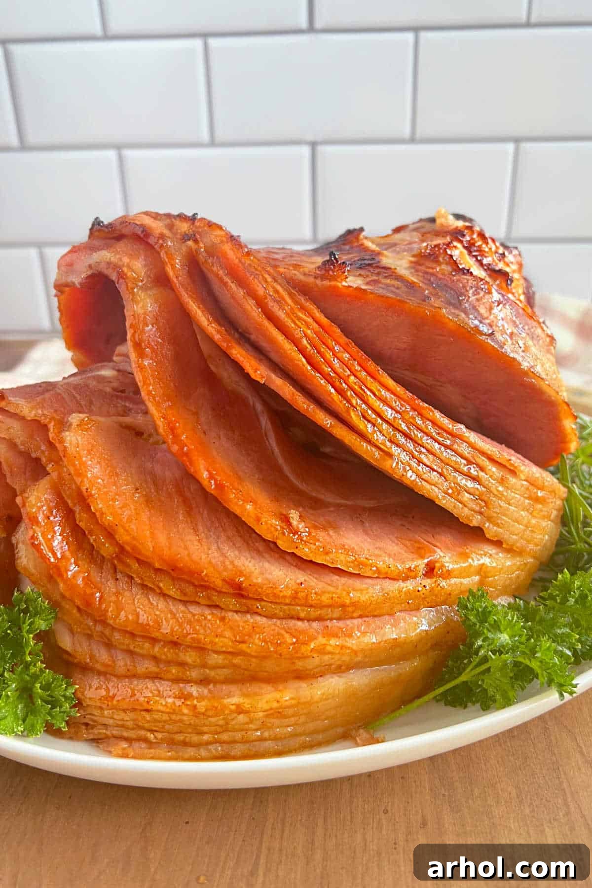 A beautifully baked spiral-cut ham with a glistening Dr. Pepper glaze, garnished with fresh parsley on a platter, ready to serve.