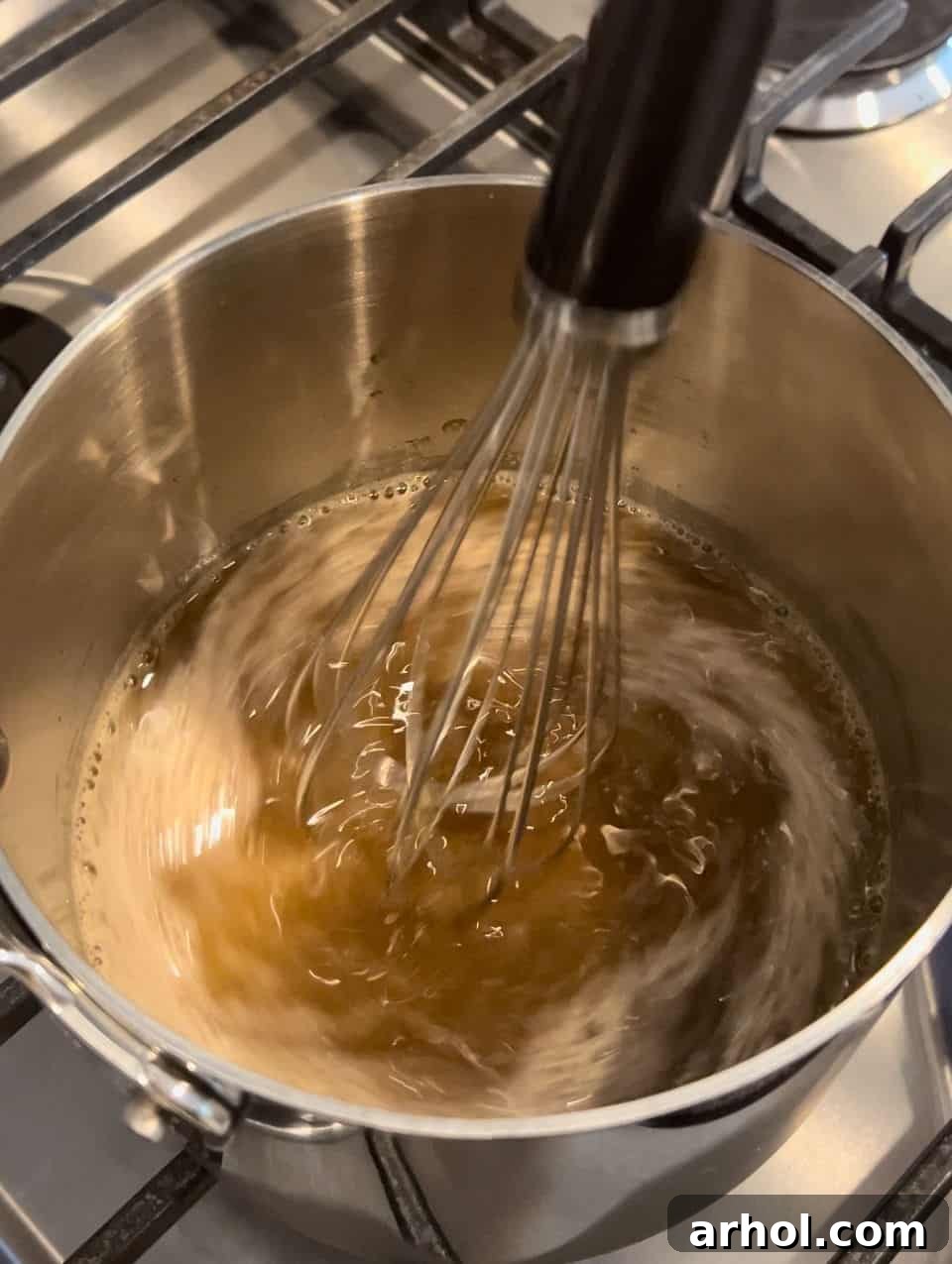 Whisking the Dr. Pepper glaze ingredients – soda, pineapple juice, brown sugar, and ground cloves – in a small pot on the stove.
