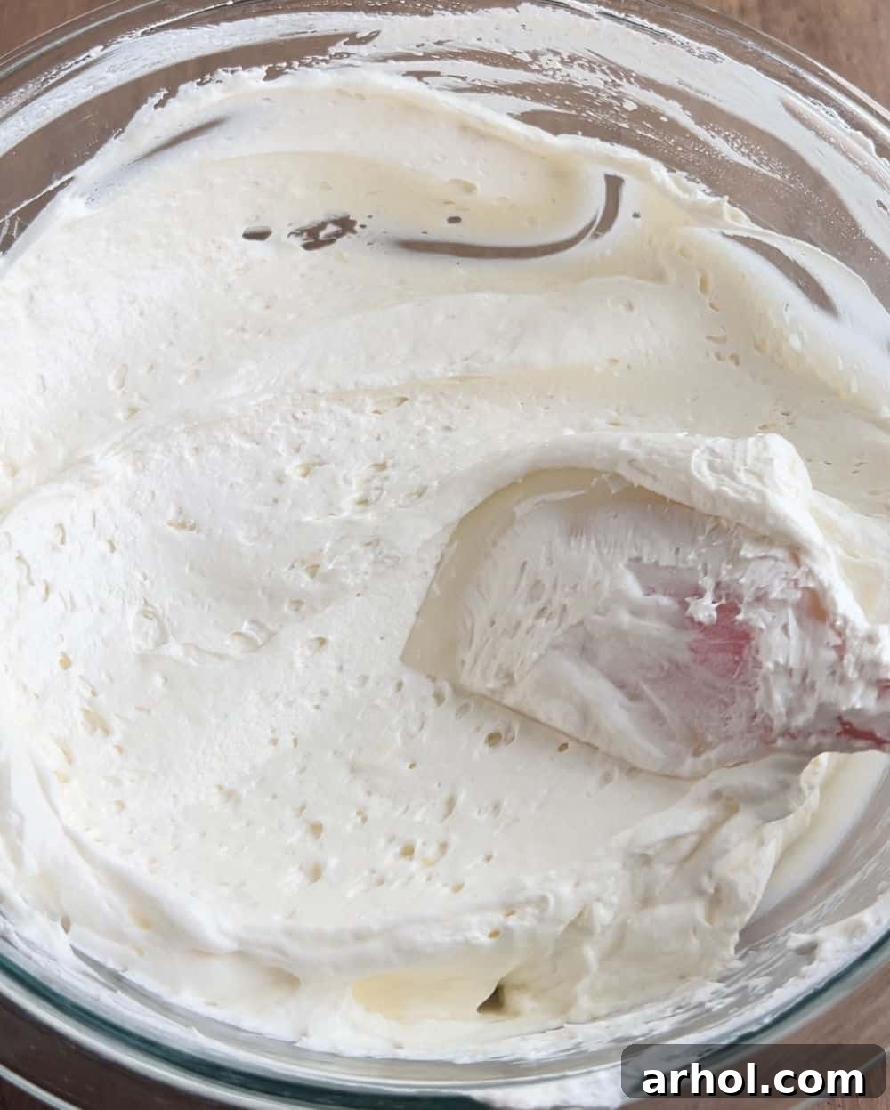 Gently folding in thawed whipped topping with a rubber spatula to maintain the airy texture and lightness of the cheesecake dip base.