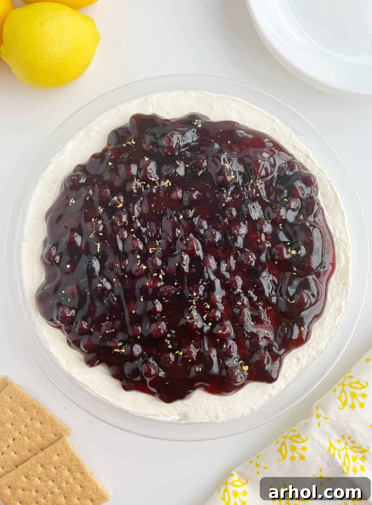 A beautifully presented Lemon Blueberry Cheesecake Dip surrounded by an assortment of delicious dippers like graham crackers and fresh berries, ready to be enjoyed at a table. Ideal for summer parties and events.
