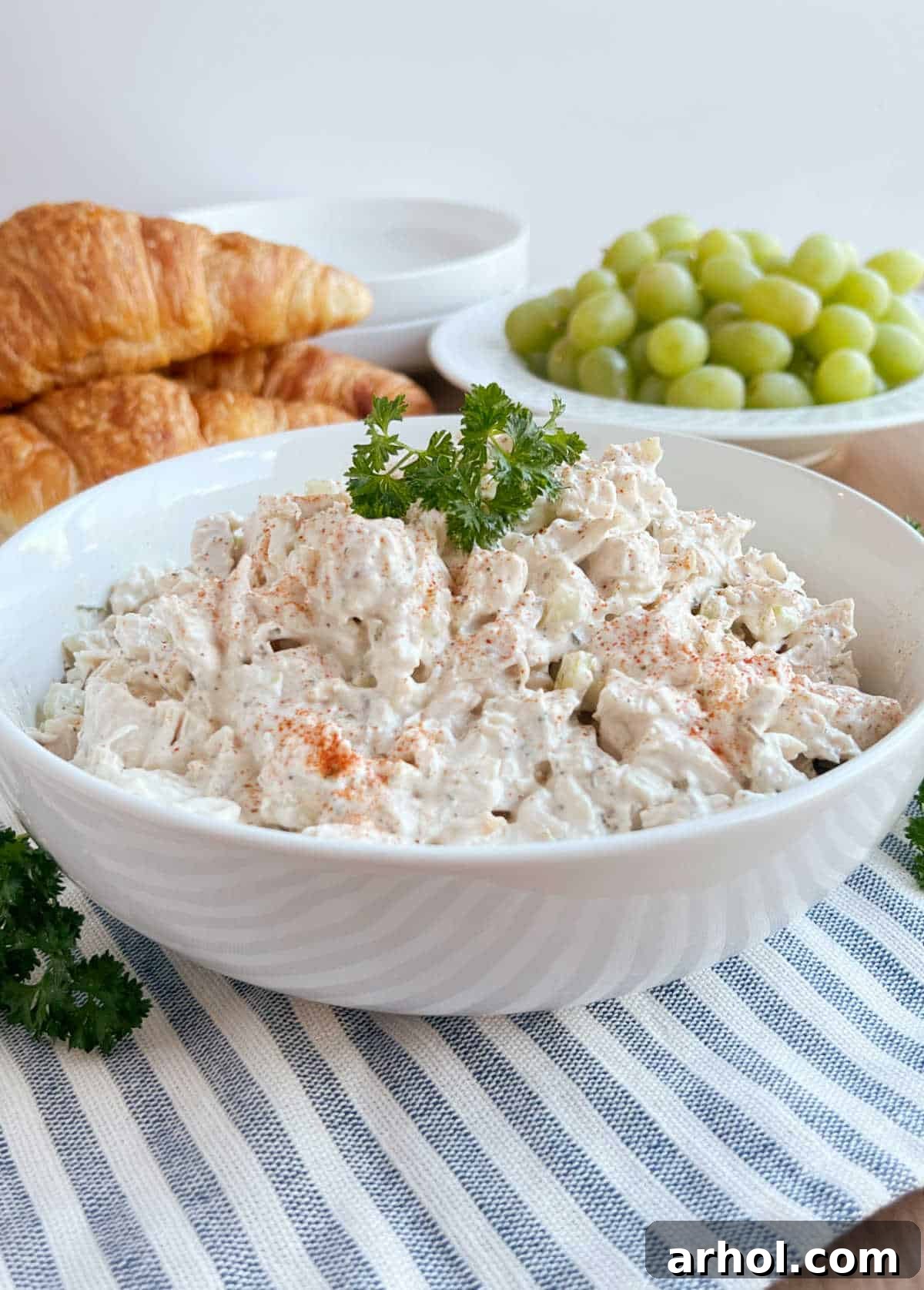 simple chicken salad bowl with croissants and grapes on the table.