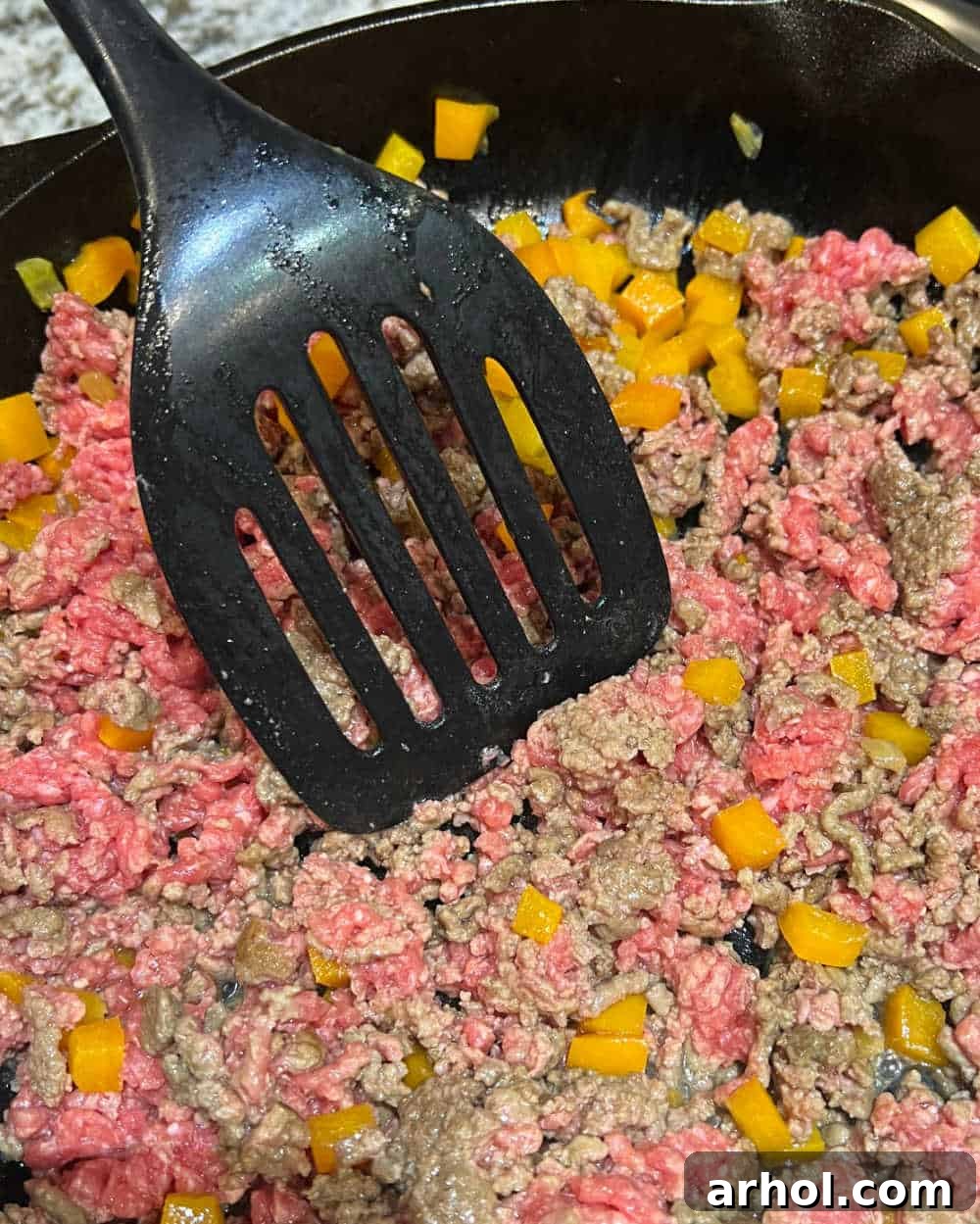ground beef in skillet with yellow bell peppers.