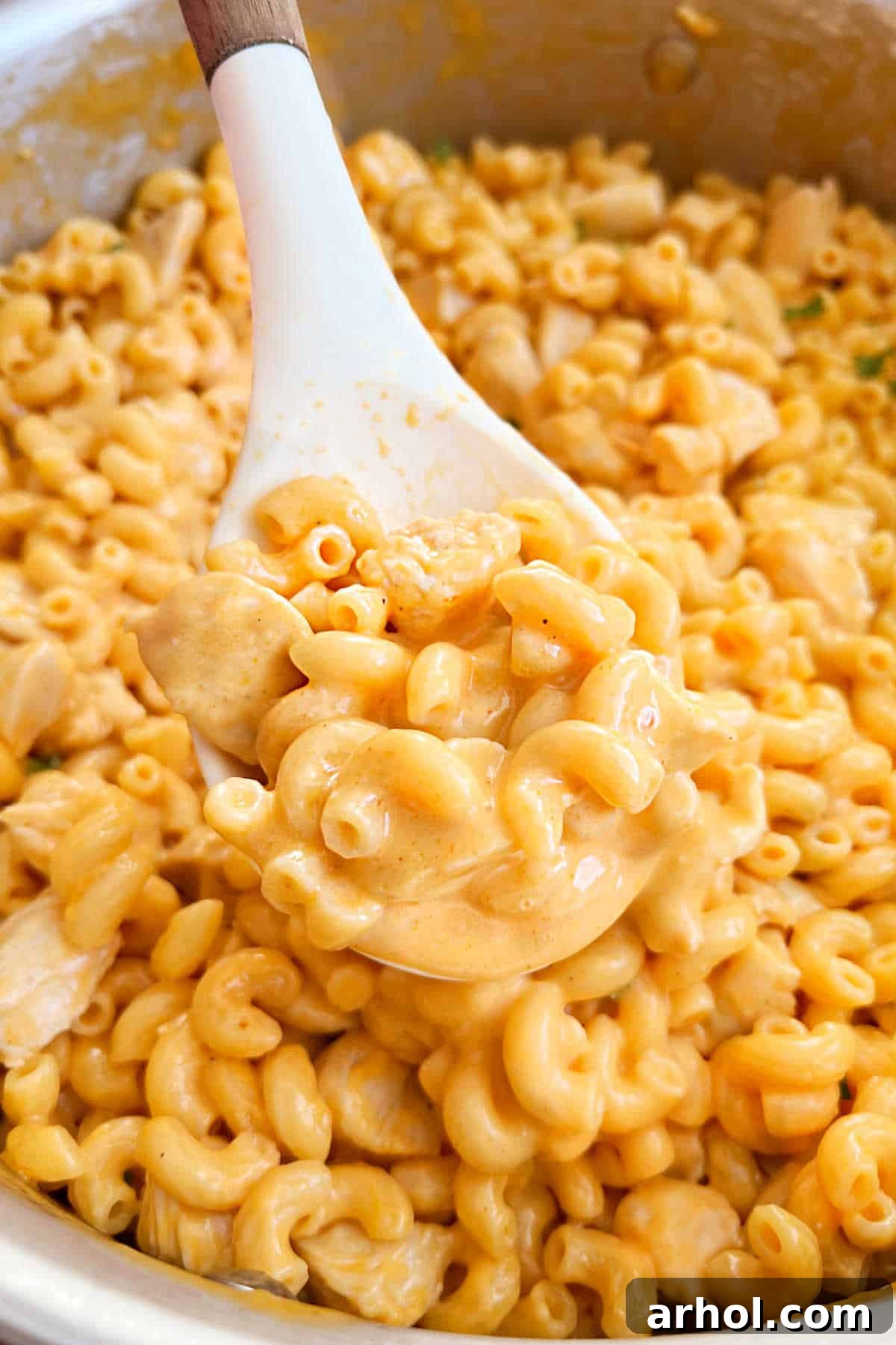 A generous serving of Buffalo Chicken Mac and Cheese being lifted with a serving spoon, showcasing the creamy texture and tender chicken pieces.