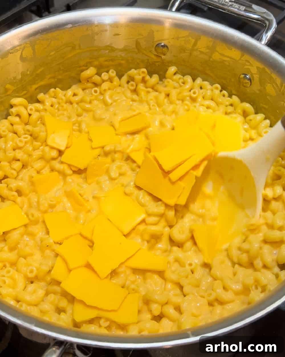 Stirring a variety of shredded cheeses into the macaroni pasta, creating a rich and creamy sauce.