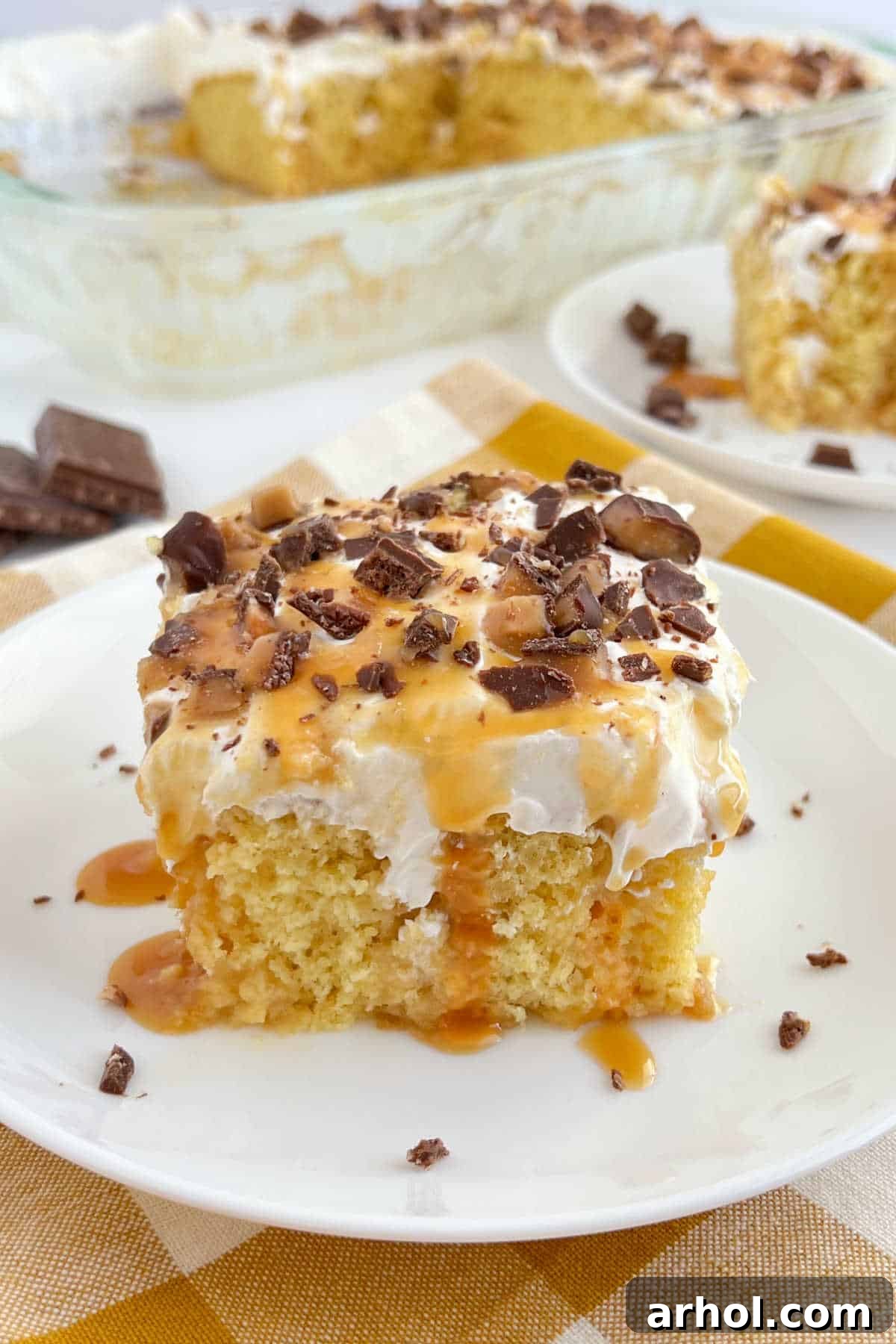 Slice of Heath bar cake with caramel sauce on white plate, highlighting its moist layers and crunchy topping.