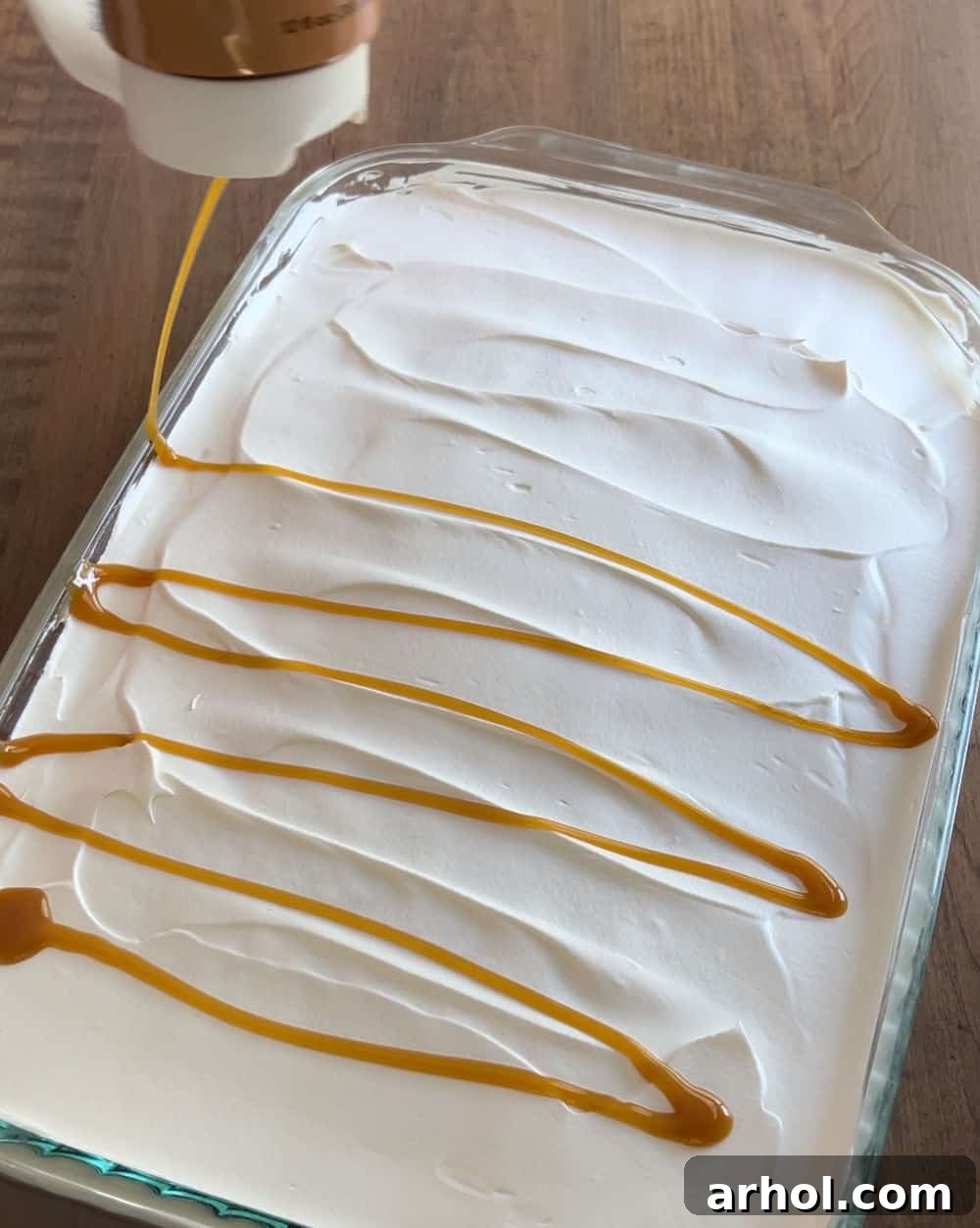 Drizzling rich caramel sauce over the fluffy whipped topping on the Heath Bar cake.