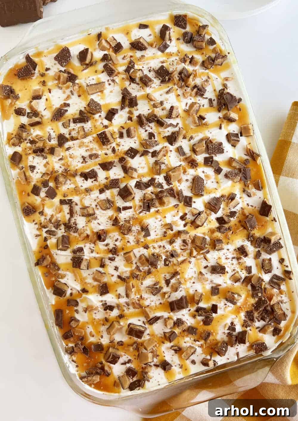 A glorious Heath bar poke cake, beautifully topped and ready to serve, sitting in a baking dish.