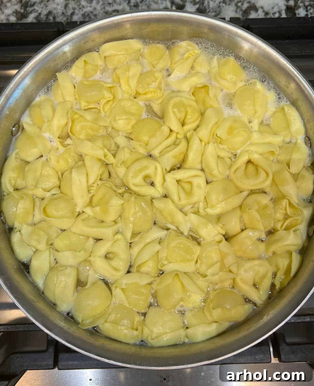 A pot of fresh tortellini boiling in salted water on a stovetop, capturing the initial step of preparing the pasta salad.