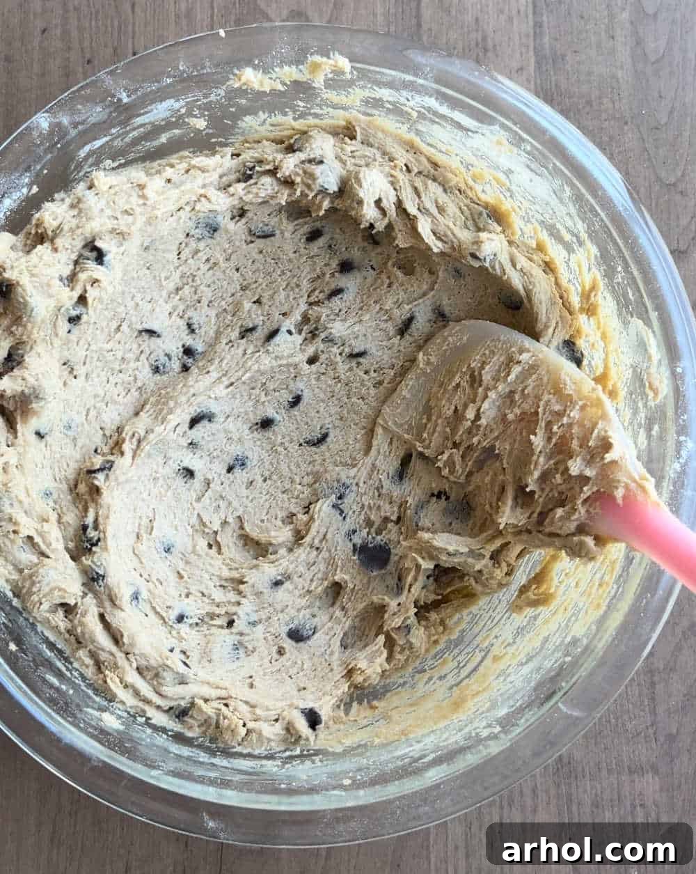 Close-up shot of cookie dough being mixed in a large bowl with a stand mixer, showcasing its soft and pliable texture.