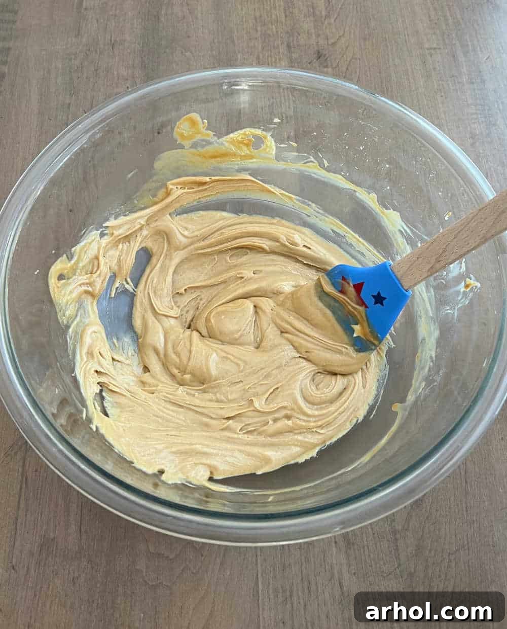Star-Spangled Snack Mix 4 Stirring the melted peanut butter, white chocolate, and butter mixture in a large bowl, creating a smooth, glossy coating.