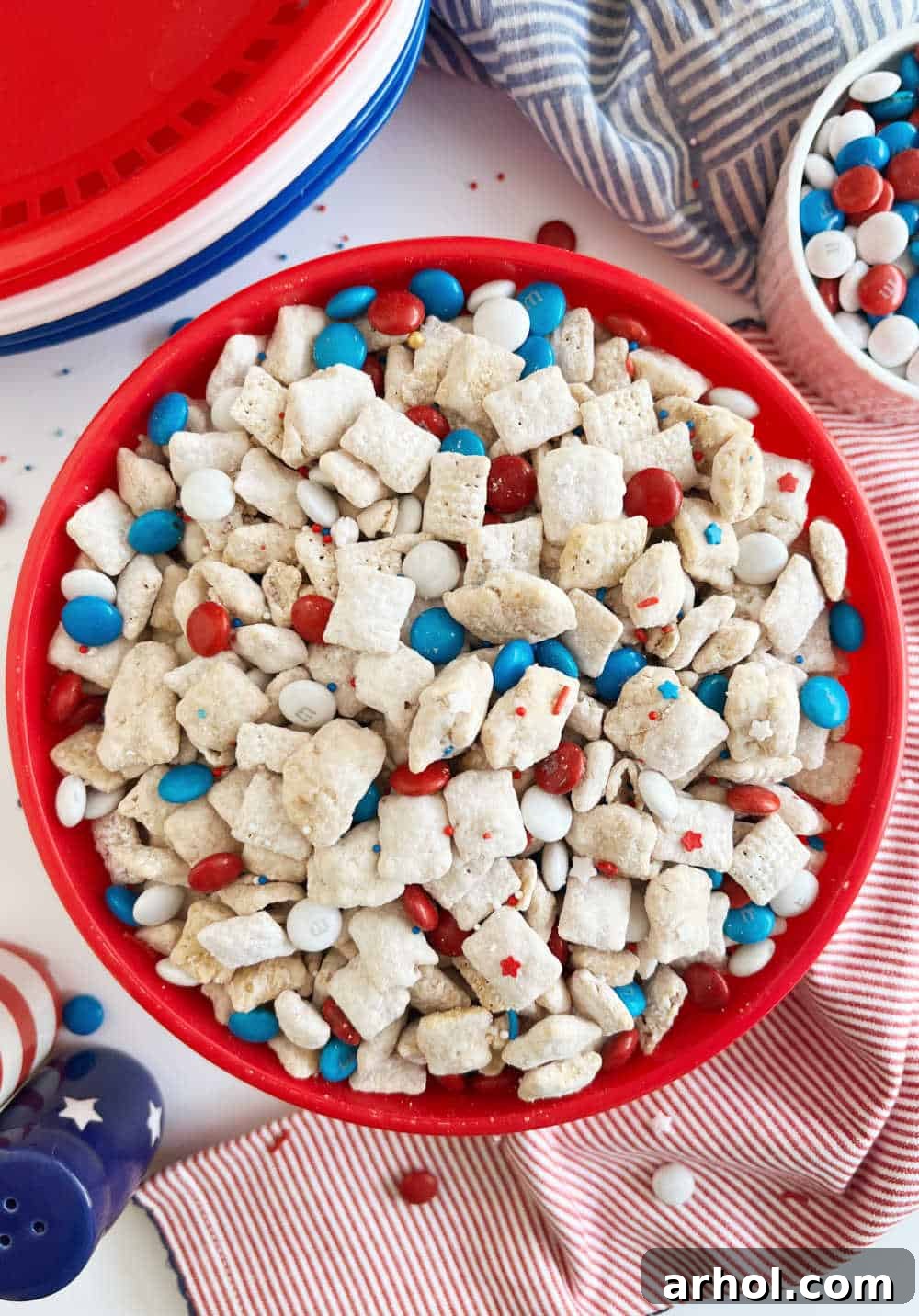 Star-Spangled Snack Mix 7 A beautiful bowl of Red White and Blue Puppy Chow displayed on a festive 4th of July table, ready for guests.