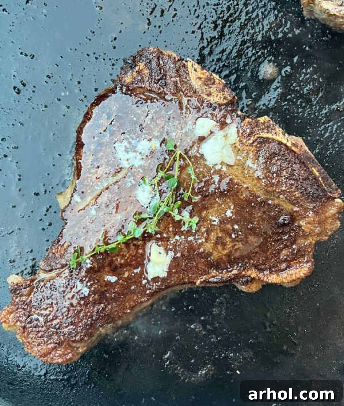 Porterhouse steak with garlic butter and thyme on a Blackstone griddle, showcasing a perfect golden-brown sear and juicy interior.