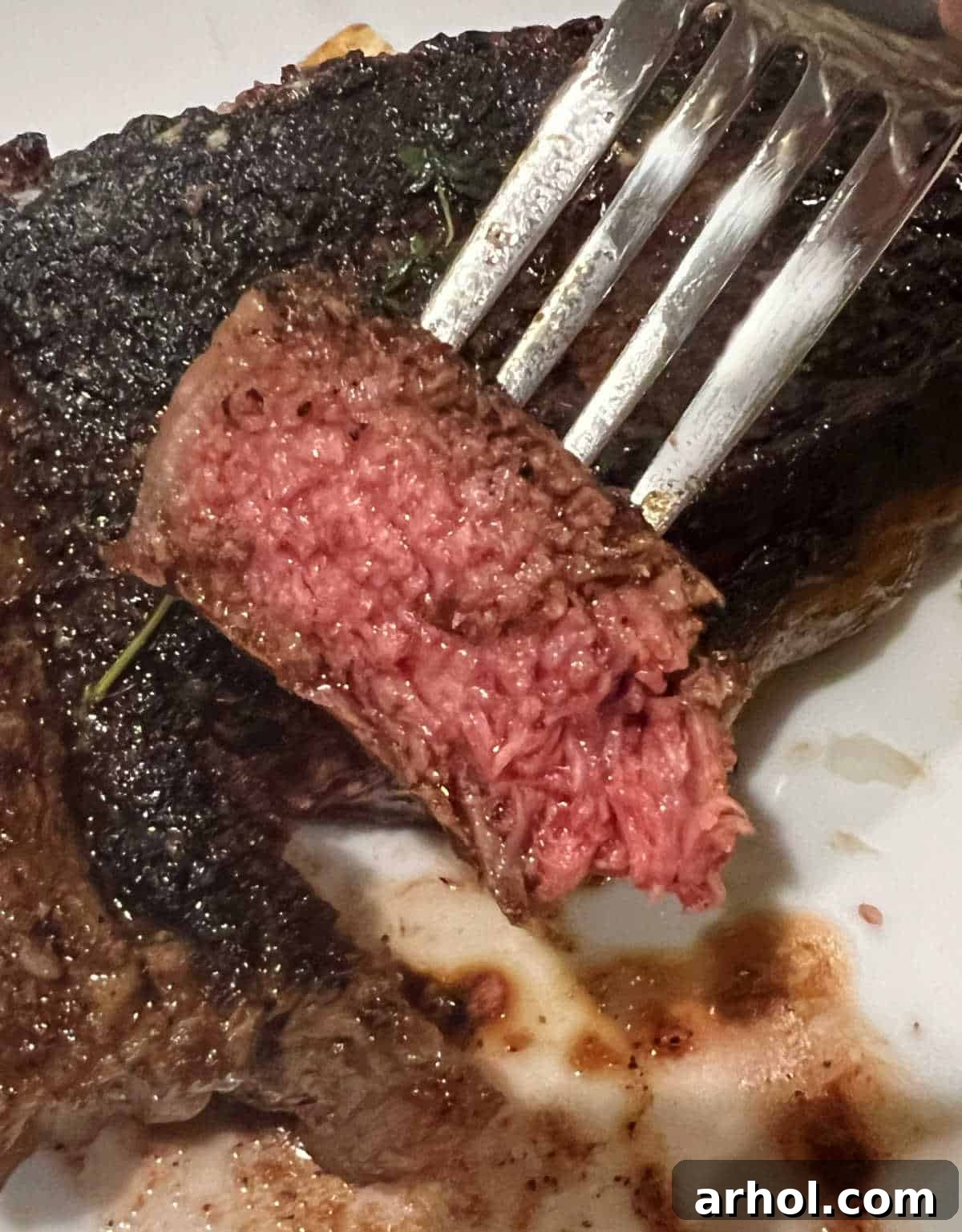 A perfectly cooked medium-rare steak, sliced against the grain, with a juicy, pink center, presented on a fork.