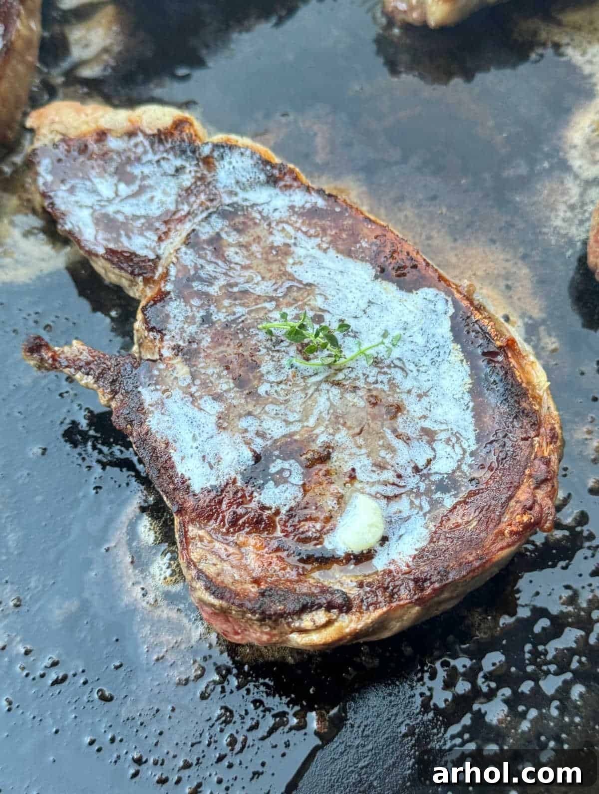 A thick, juicy ribeye steak sizzling on a hot flat-top griddle, surrounded by rendering fats, ready for a perfect sear.