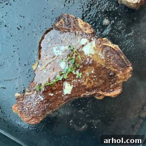 Porterhouse steak beautifully seared on a Blackstone griddle, generously basted with garlic butter and garnished with fresh thyme.