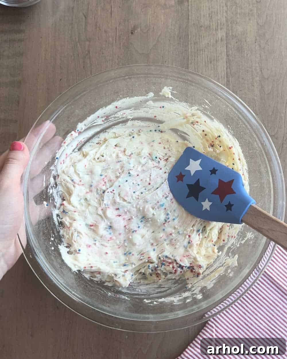 Gently folding vibrant red, white, and blue sprinkles into the cookie dough with a star-shaped spatula, adding a festive touch.