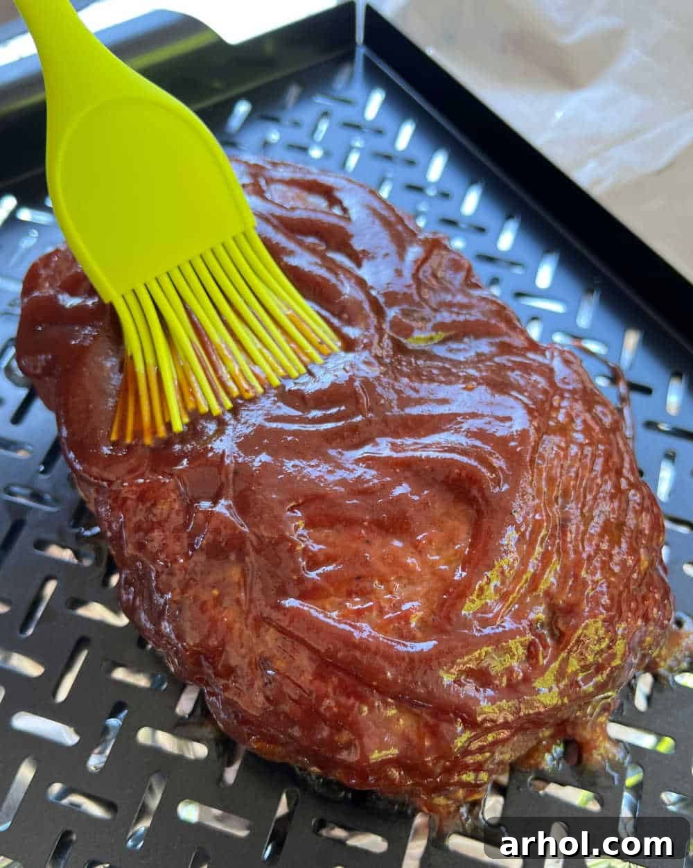 Smoky Barbecue Glazed Meatloaf 6 Brushing BBQ sauce onto a smoked meatloaf during the cooking process.