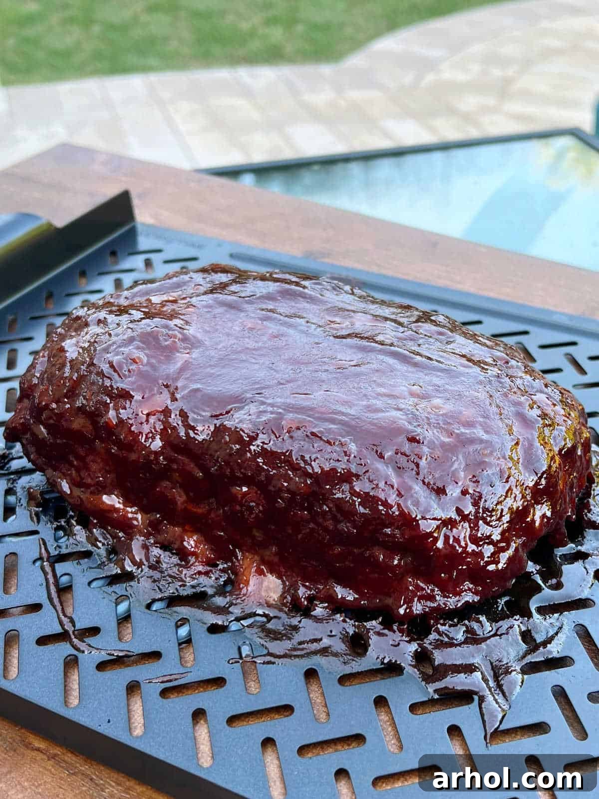 Smoky Barbecue Glazed Meatloaf 7 Fully cooked smoked meatloaf with BBQ glaze resting in a backyard setting.
