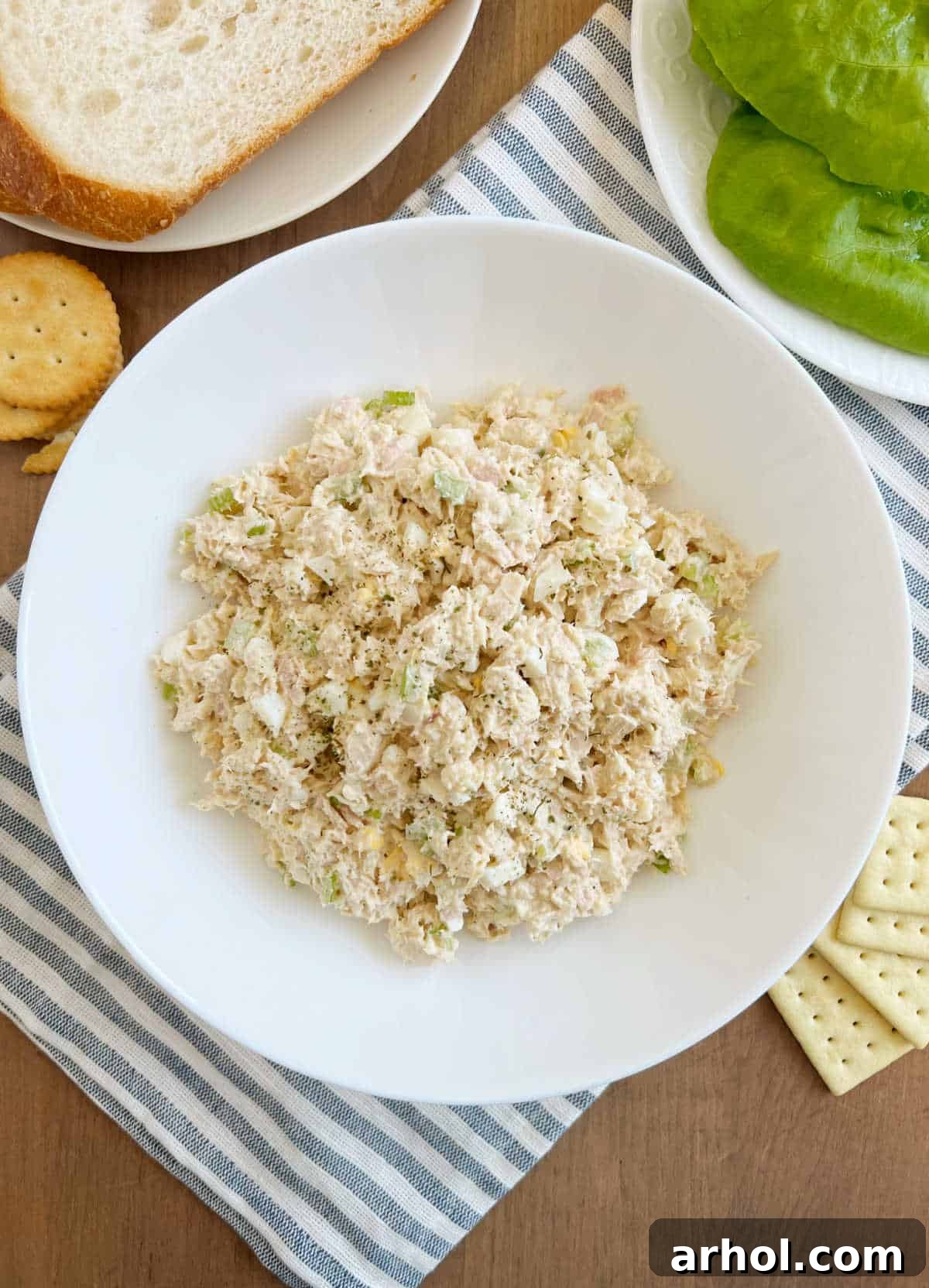 A vibrant bowl of classic tuna salad with egg and finely chopped celery, ready to be served on a rustic wooden table.