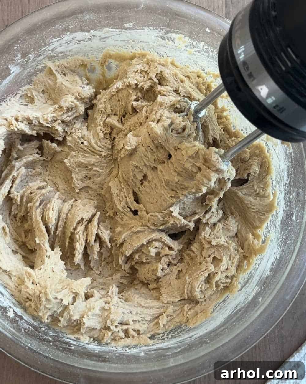 Electric mixer creaming butter and sugar in a large blue bowl, with ingredients visible around it.
