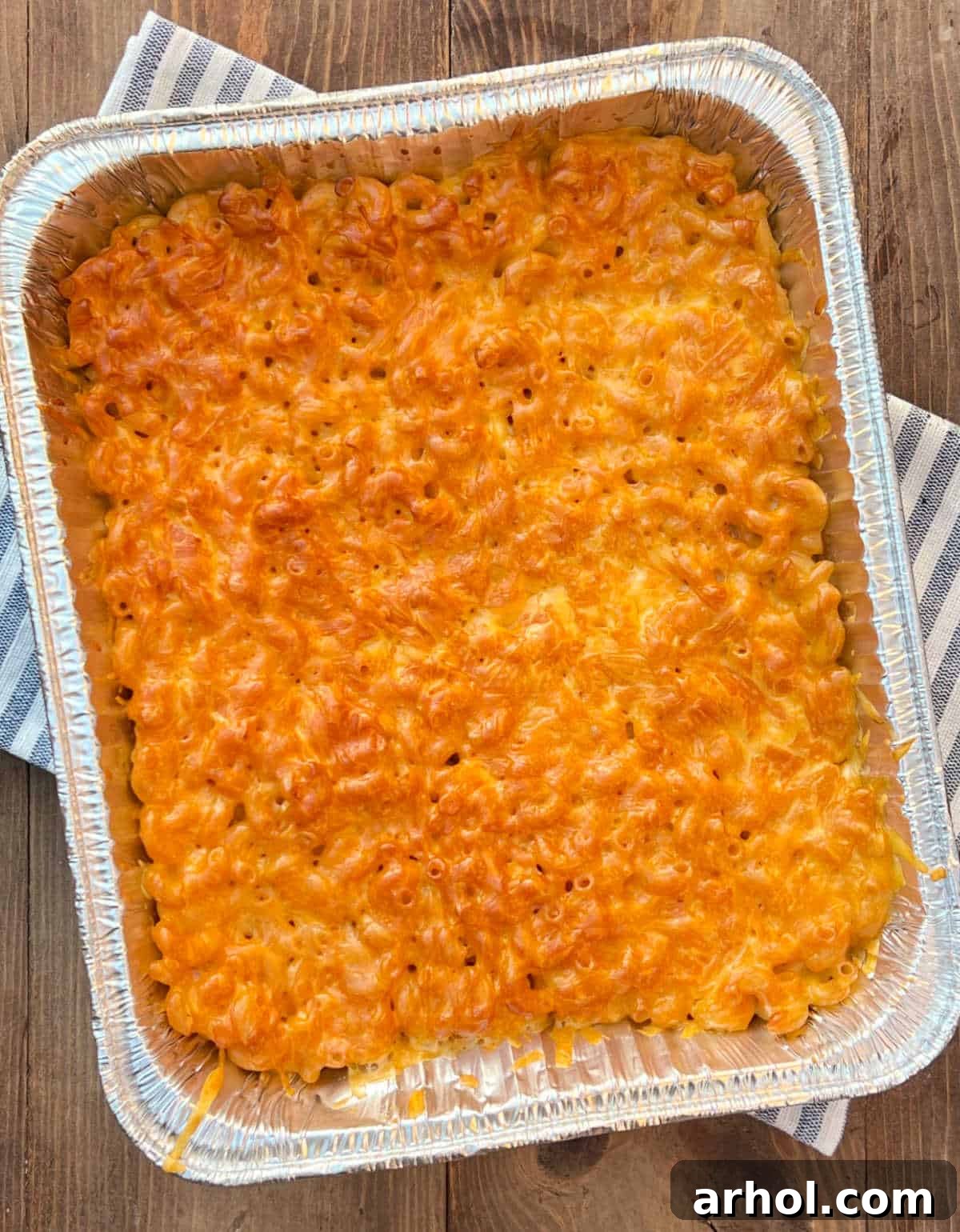 A close-up shot of a pan of freshly smoked mac and cheese, showcasing its bubbly, cheesy, golden-brown crust and the rich, creamy interior.