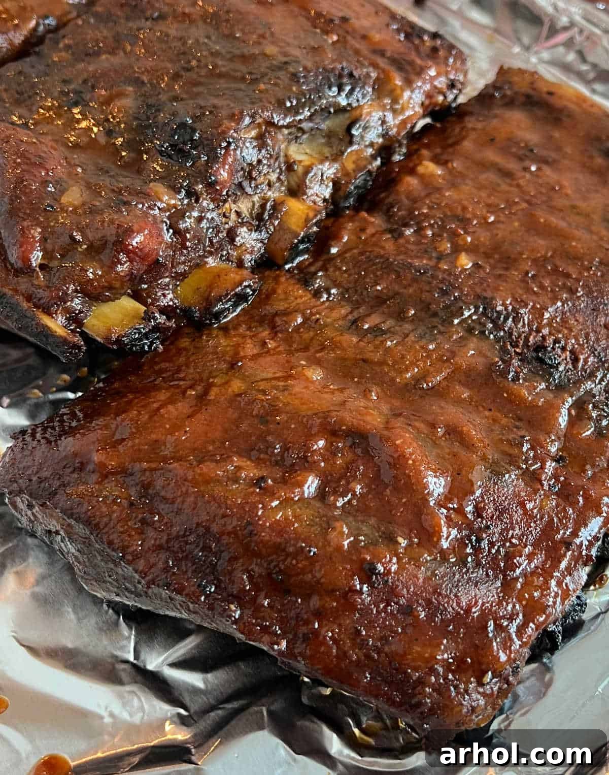 A full rack of smoked St. Louis ribs with glistening BBQ sauce, served on a tray, showcasing their tenderness.