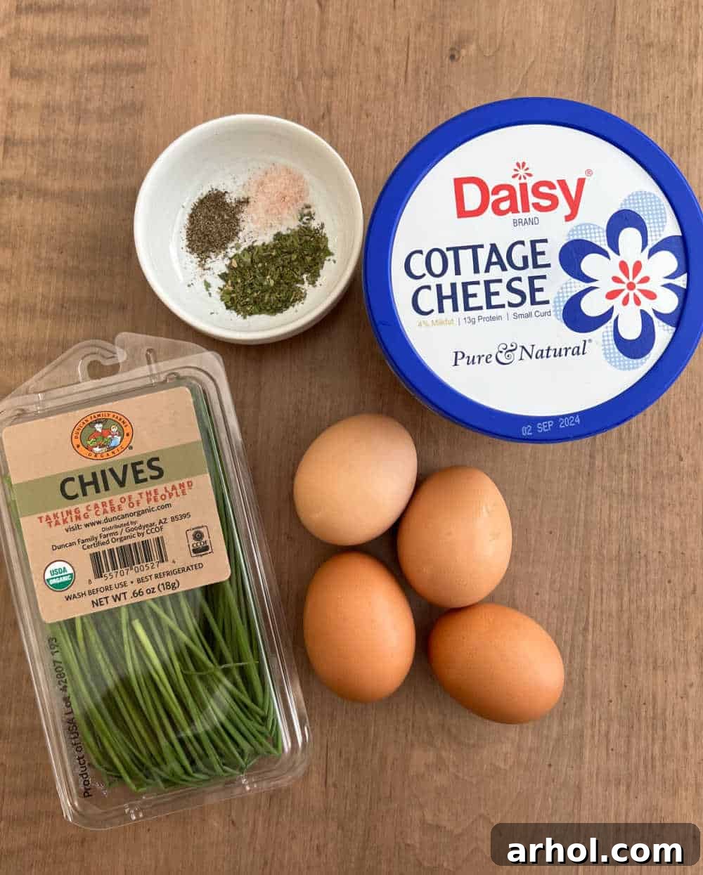 High Protein Cottage Cheese Egg Scramble 3 Fresh ingredients laid out: cottage cheese, eggs, vibrant chives, and essential seasonings, ready for making high-protein scrambled eggs.