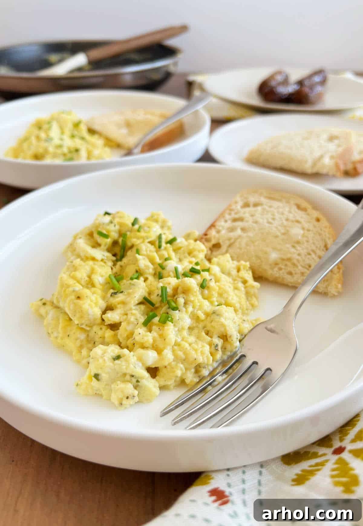 High Protein Cottage Cheese Egg Scramble 8 Two plates of creamy cottage cheese scrambled eggs on a rustic breakfast table, garnished with fresh chives, ready to be enjoyed.
