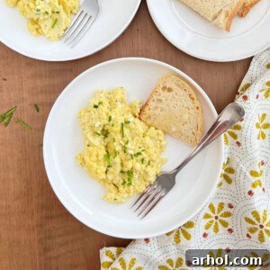 Creamy scrambled eggs with cottage cheese and fresh chives on a plate, ready to be served.