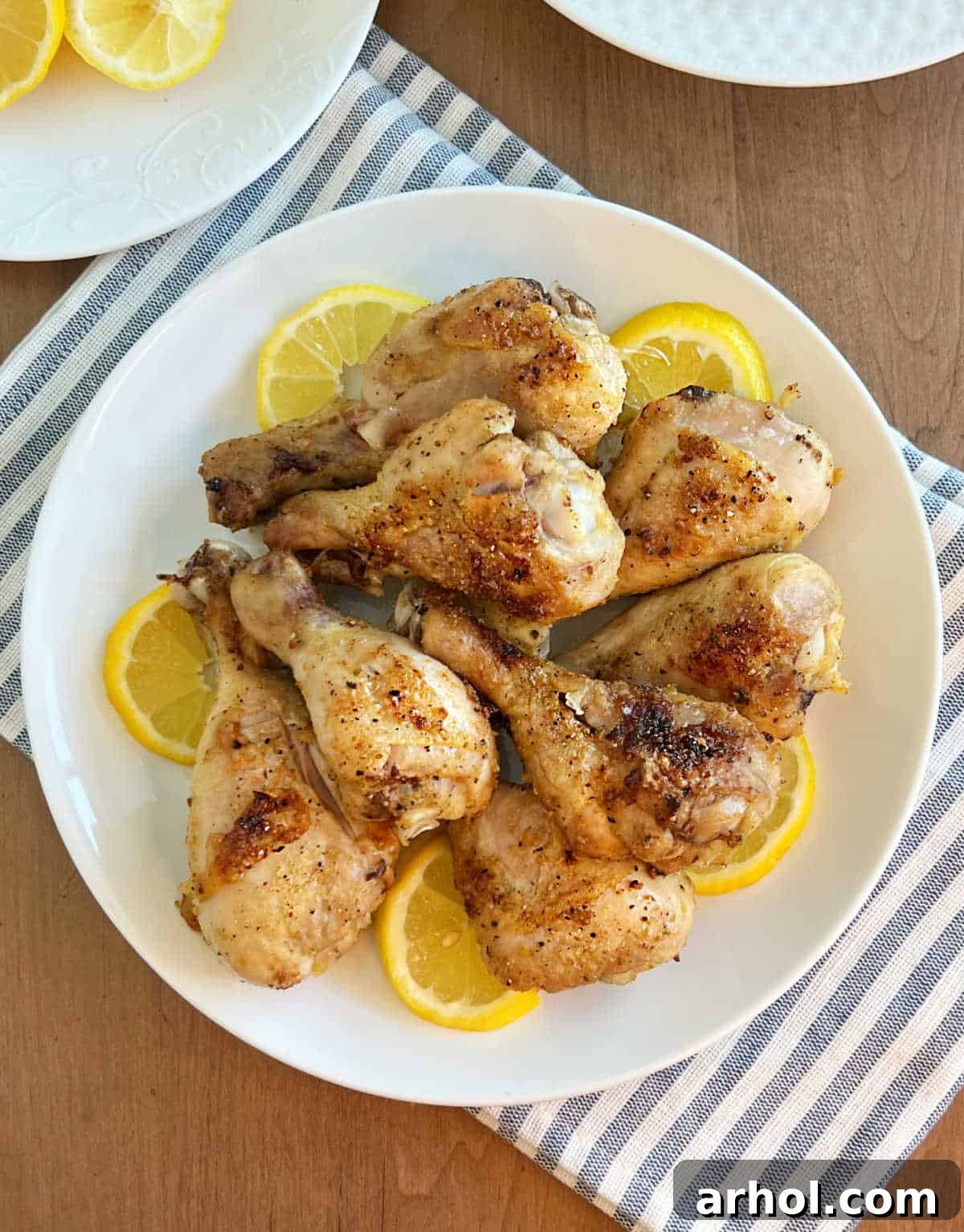 Crispy lemon pepper baked chicken legs with fresh lemon slices on a serving platter, ready to be enjoyed.
