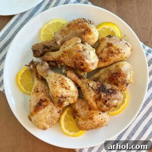 A plate of golden baked chicken legs garnished with fresh lemon slices, highlighting the delicious result of the recipe.